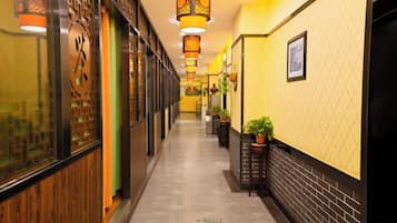 A corridor with wooden paneling, a clock, and hanging lanterns.