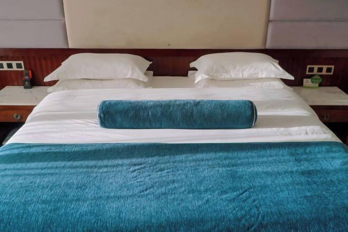 A bed with white linens and a blue blanket, wooden headboard, and bedside tables with lamps.