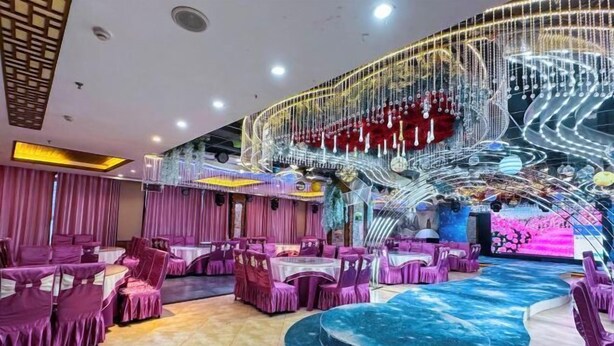 A spacious indoor area with round tables and chairs, a central stage, and a decorative spiral structure. - Jinheyuan International Hotel Guide (Guide)
