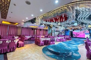 Un espacio interior amplio con mesas y sillas redondas, un escenario central y una estructura espiral decorativa.