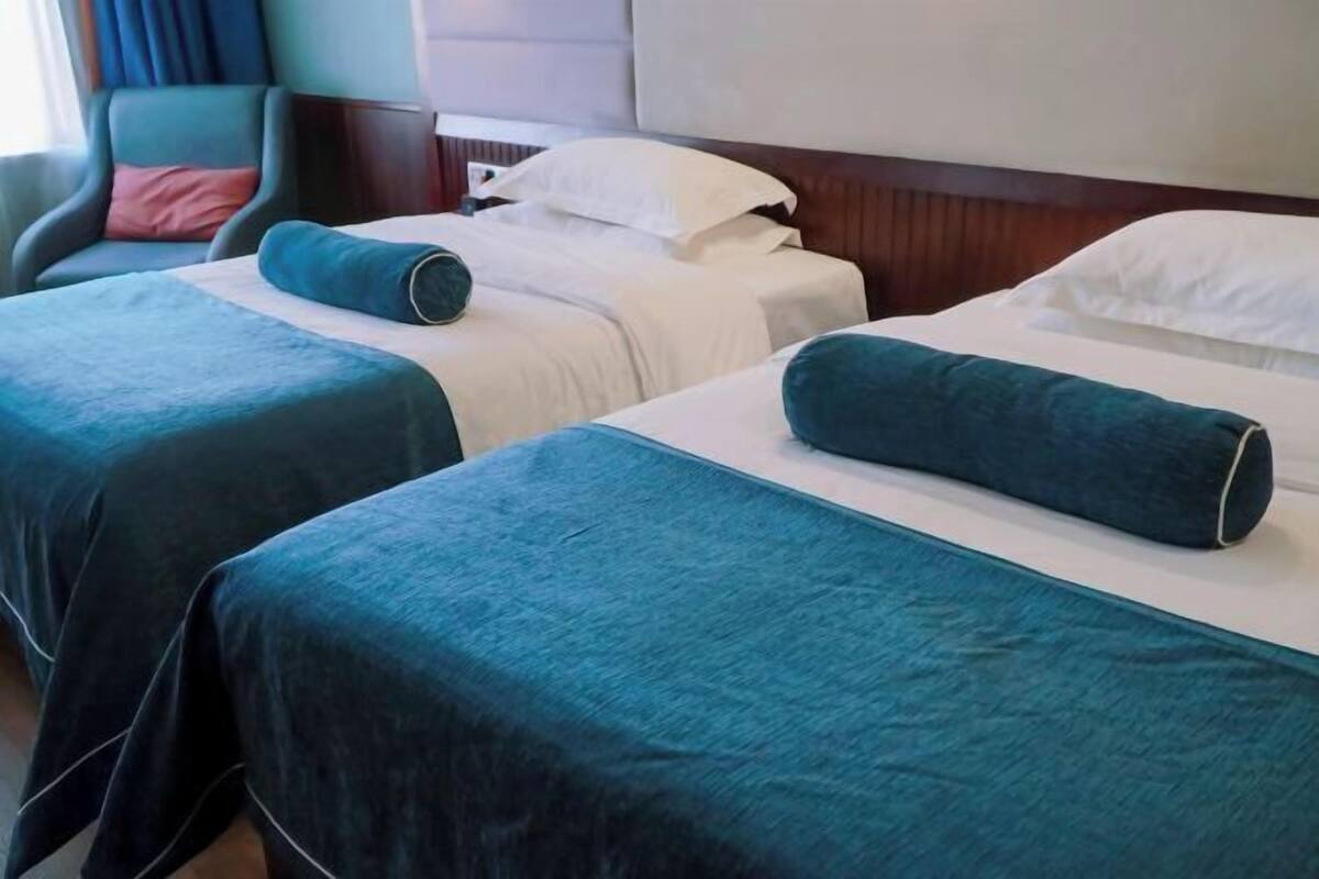 A hotel room with two single beds, a chair, and a wooden headboard.