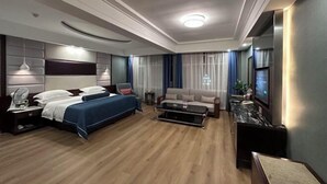 A hotel room with a bed, a sofa, a coffee table, a TV, and a desk with a lamp. - Jinheyuan International Hotel Guide (Guide)