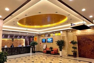 Un vestíbulo de hotel con una recepción, zona de estar y un gran techo decorativo.