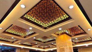 A hotel lobby with a modern ceiling design featuring geometric patterns and recessed lighting. - Jinheyuan International Hotel Guide (Guide)