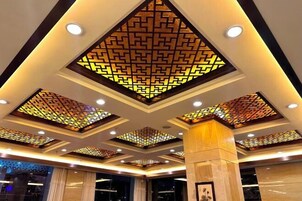 Vestíbulo de hotel con un diseño moderno de techo que presenta patrones geométricos e iluminación empotrada.