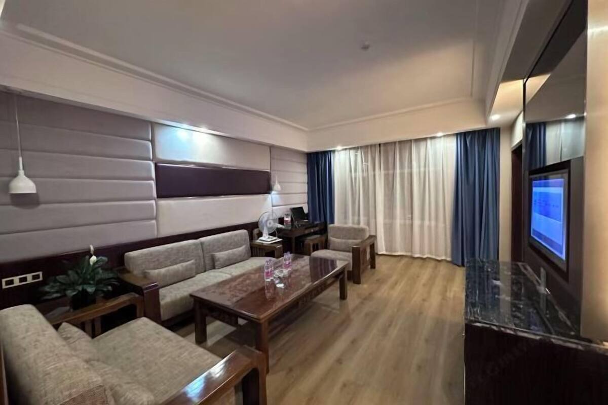A modern living room with a sofa set, a coffee table, a TV, and a large window with curtains.