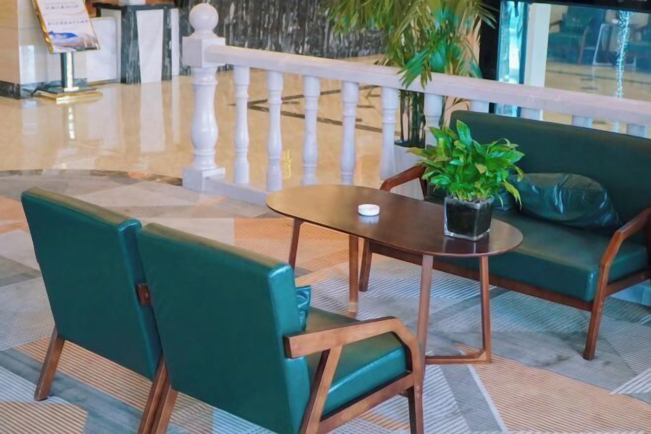 A lobby with a marble floor, a reception desk, a white railing, and green upholstered seating.