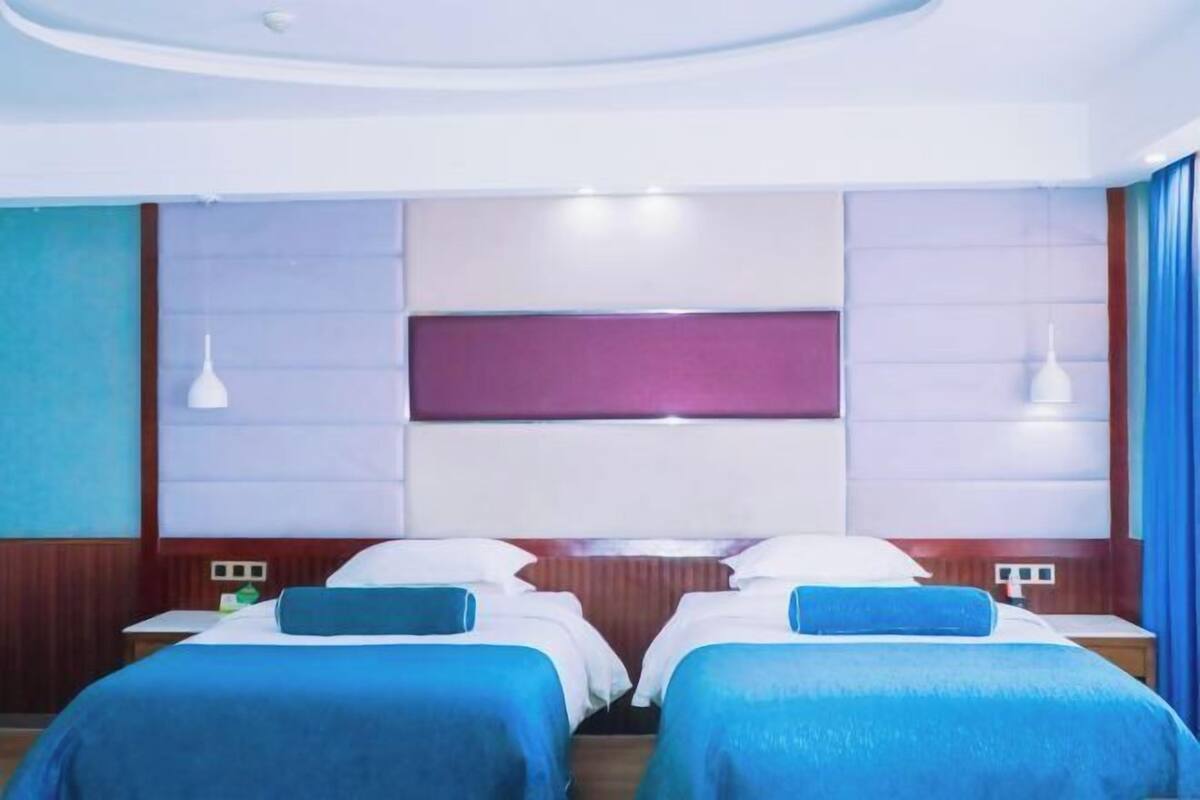 A hotel room with two beds, a large window, and a modern ceiling design.