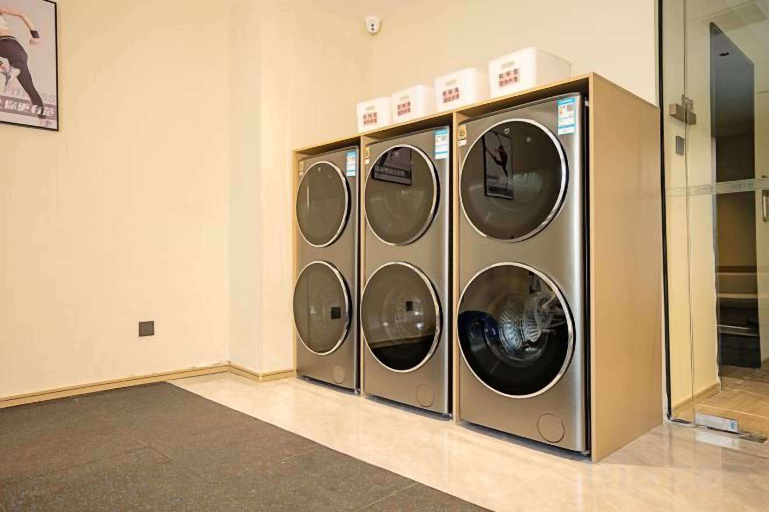 Une rangée de six machines à laver à chargement frontal, disposées les unes sur les autres, dans un couloir.