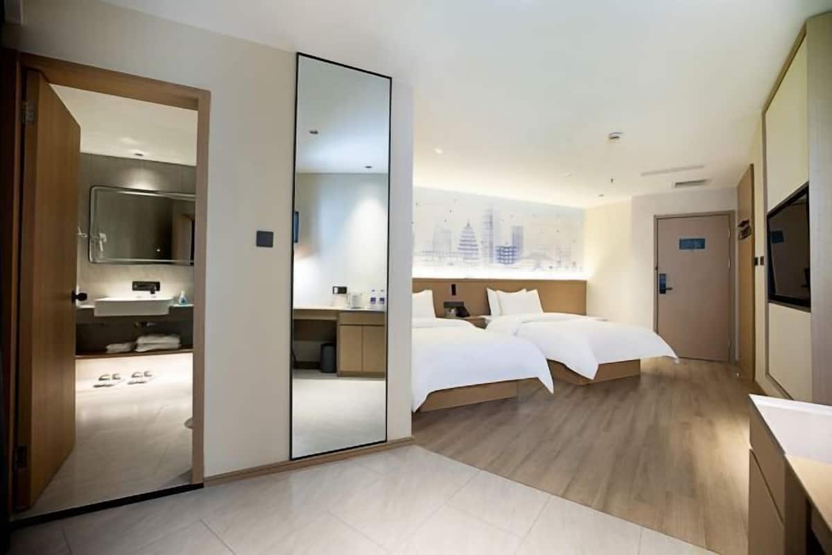 Una habitación de hotel moderna con una cama grande, un escritorio, un espejo y vistas a la ciudad.