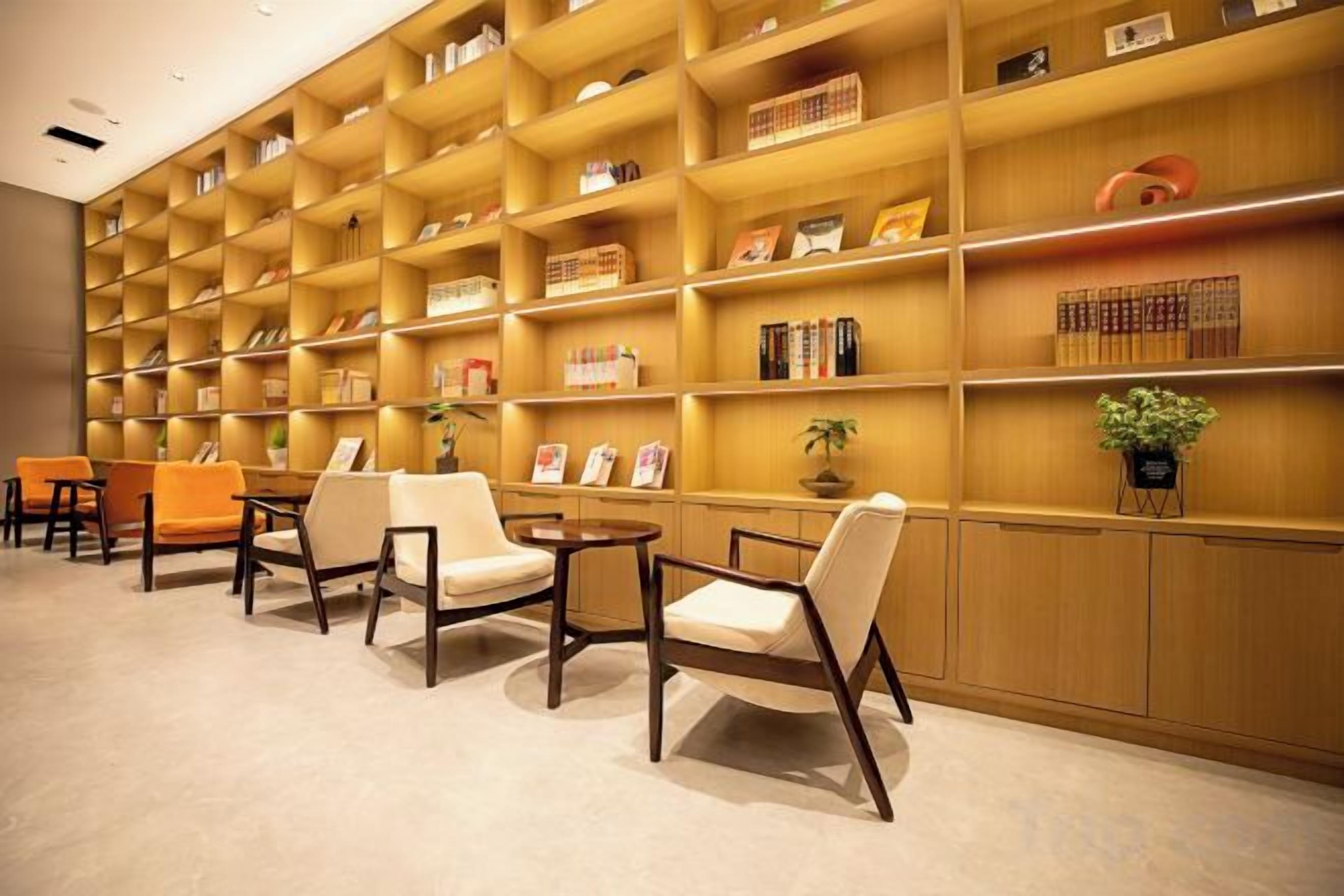 Una biblioteca con scaffali, sedie e una pianta in vaso.
