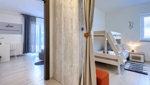 Una habitación moderna con una cama litera, un escritorio con silla y un ventanal con cortinas.