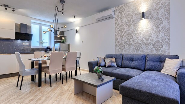 Una sala de estar moderna con un sofá gris, una mesa de comedor con sillas y una mesa de centro.