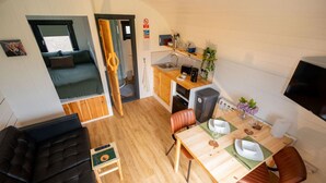 A compact living space with a sofa, a dining table, and a kitchenette.