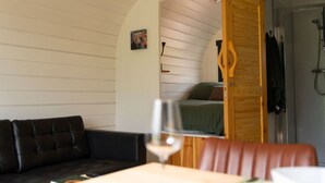 A cozy room with a wooden door leading to a bathroom, a green bed, and a black leather sofa. - Aonach Mor Pod near Fort William (Caol)