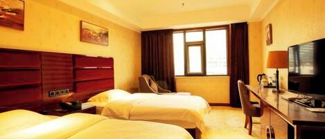 A hotel room with two beds, a desk with a television, a chair, and a window with curtains.