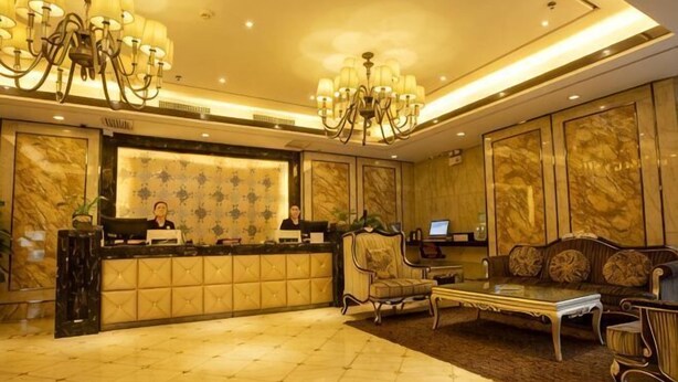 Zona de recepción con suelo de mármol, mostrador de recepción, sofá, mesa de centro y candelabro.