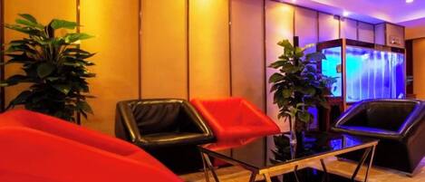 A hotel lobby with seating areas, a reception desk, and a decorative wall.