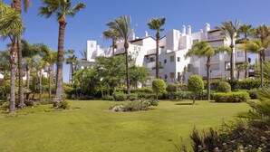 A hotel with multiple white buildings, surrounded by well-maintained lawns and palm trees.