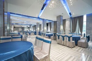 Un salón de banquetes con mesas redondas, sillas y un piso de mármol pulido.