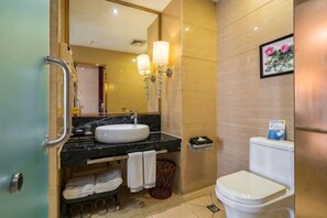 A bathroom with a sink, mirror, towel rack, toilet, and trash bin. - Jinhuafu Hotel (Longchang)