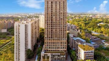 Un edificio de gran altura con varios pisos, rodeado de otros edificios residenciales y vegetación.