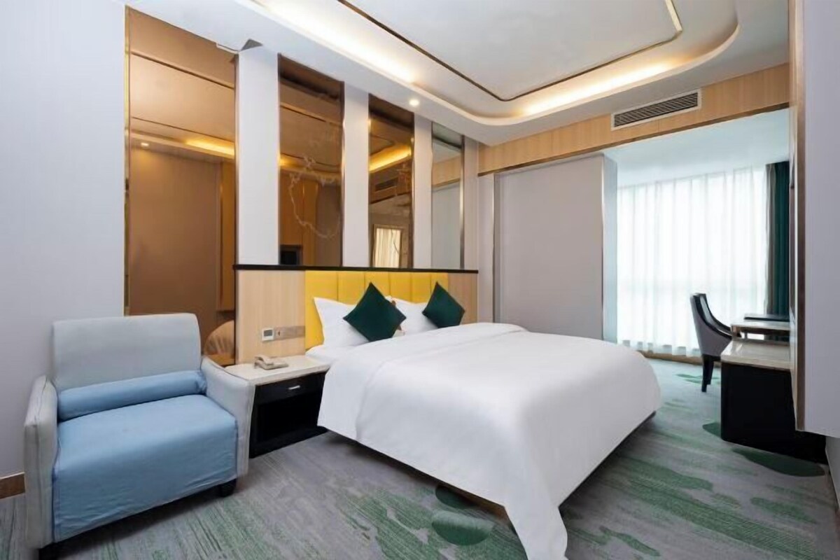 A modern hotel room with a large bed, a seating area, and a desk.