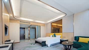 Una habitación de hotel moderna con una cama grande, un sofá verde, una mesita pequeña y un espejo.