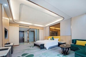 A modern hotel room with a large bed, a green sofa, a small table, and a mirror. - Jinhuafu Hotel (Longchang)