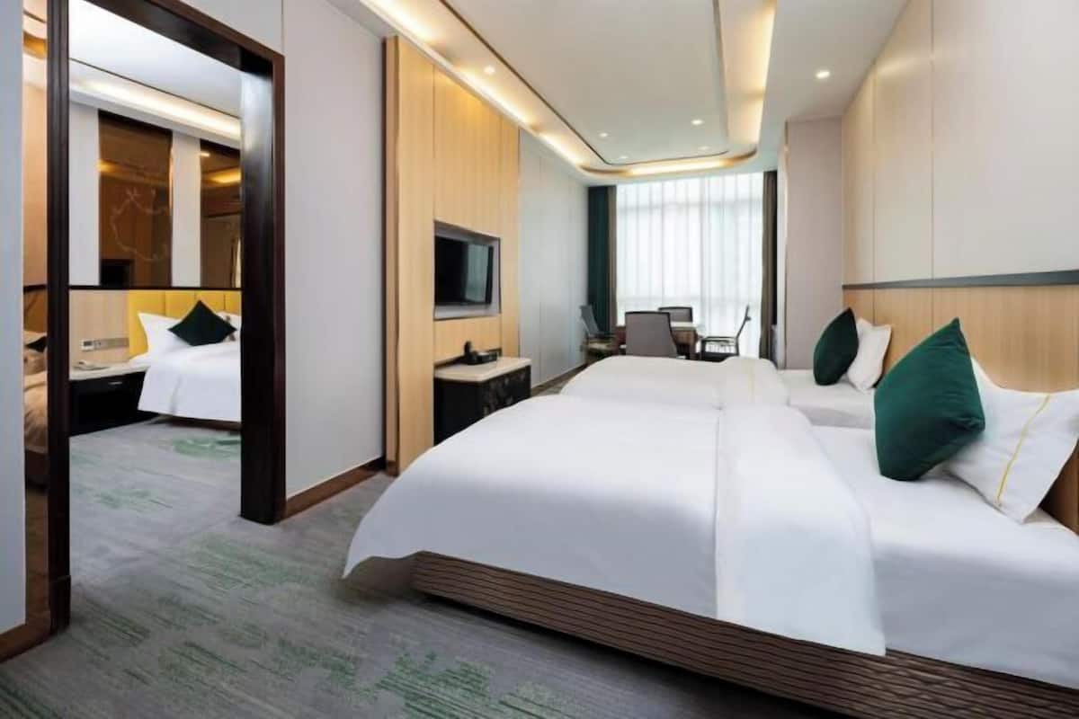 Una camera d'hotel con un letto grande, una TV, una scrivania e uno specchio.