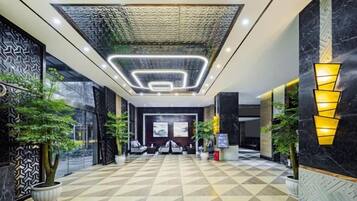 A hotel lobby with a geometric patterned floor, a central seating area, and modern lighting fixtures.