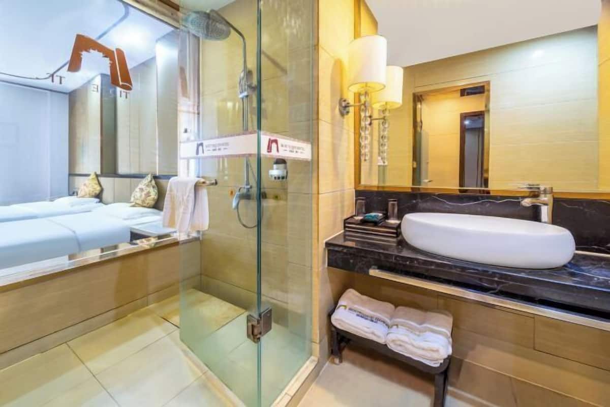Un bagno moderno con doccia vetrata, uno specchio grande, un lavandino bianco e un mobile con piano in marmo.