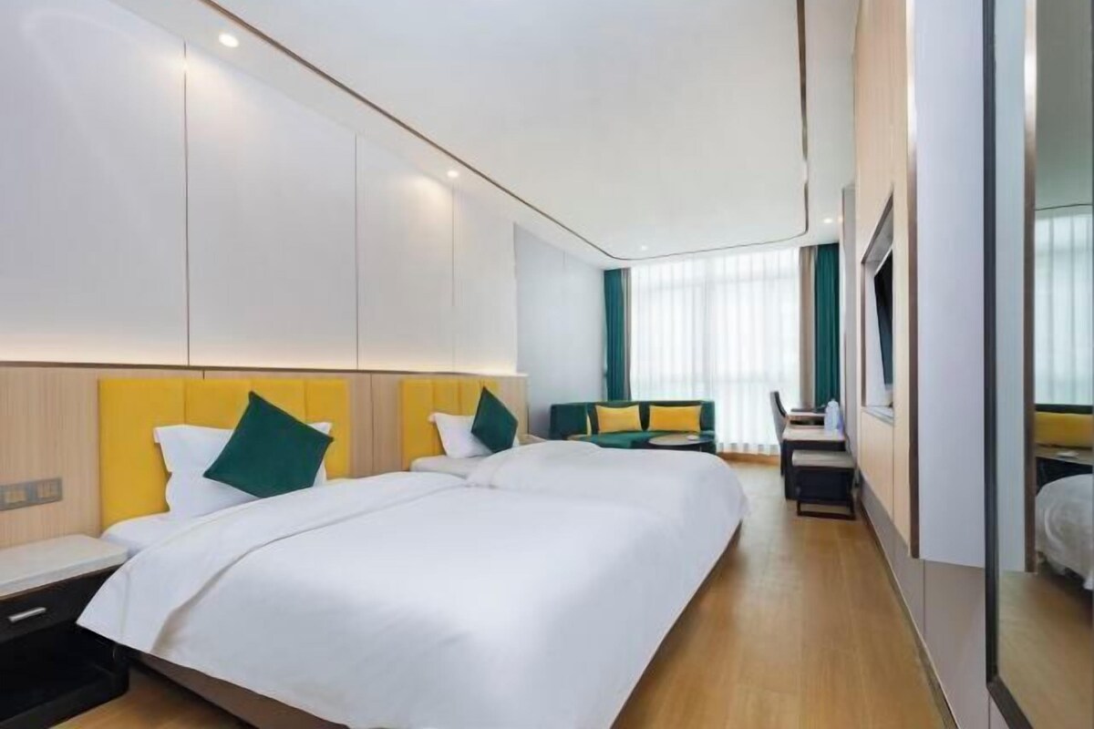 A hotel room with a large bed, a desk, and a seating area.