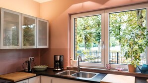 Eine moderne Küche mit integriertem Geschirrspüler, einer Kaffeemaschine und einem Fenster mit Blick auf eine von Bäumen gesäumte Straße.