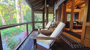 A covered porch with wooden chairs and a view of a lush garden.