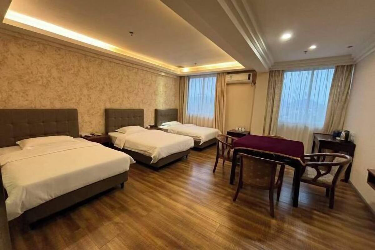 Une chambre d’hôtel avec trois lits, un bureau et une chaise.