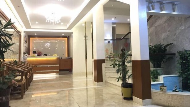 Een hotel lobby met een receptiebalie, een zithoek en potplanten.