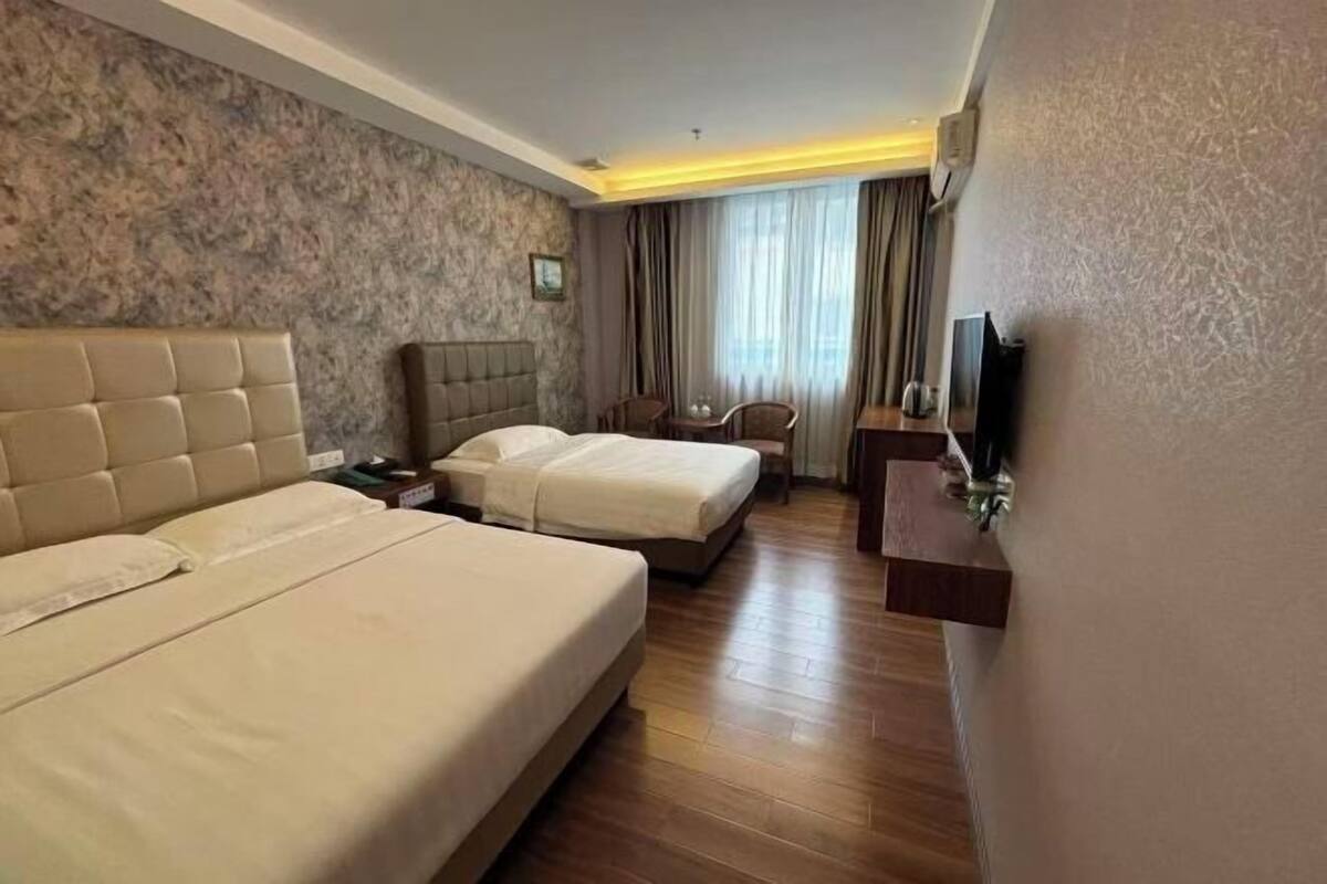 Une chambre d’hôtel avec deux lits, une télévision, un bureau et une chaise.