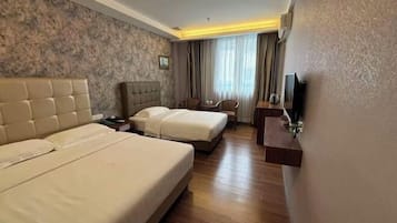 A hotel room with two beds, a television, a desk, and a chair.