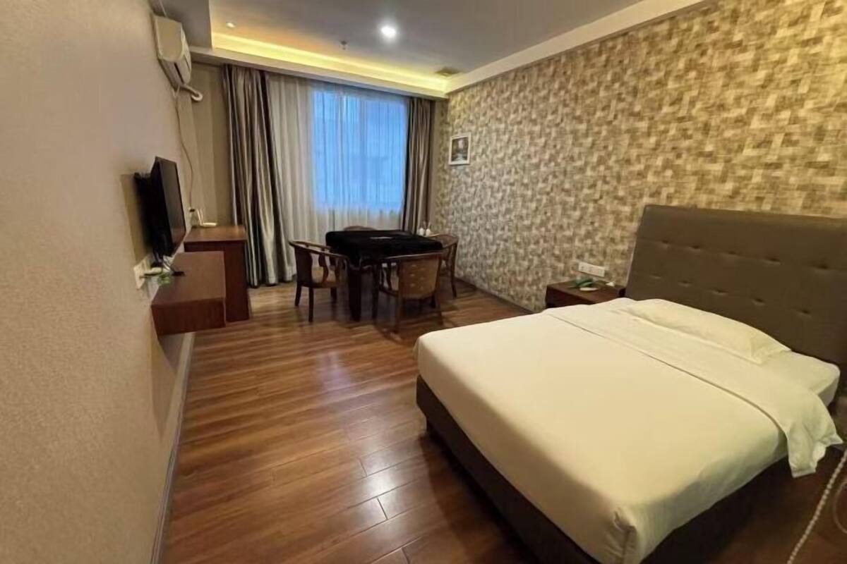 Une chambre d’hôtel équipée d’un lit, d’un bureau, d’une chaise, d’une télévision et d’une fenêtre avec des rideaux.