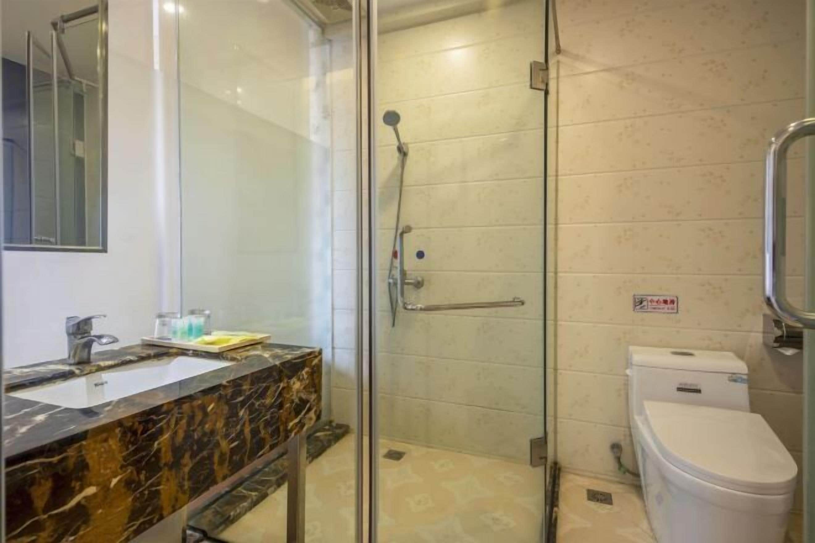 A bathroom with a glass-enclosed shower, a marble sink, and a white toilet.