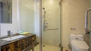 A bathroom with a glass-enclosed shower, a marble sink, and a white toilet.
