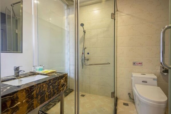 Een badkamer met een glazen douchecabine, een marmeren wastafel en een wit toilet.