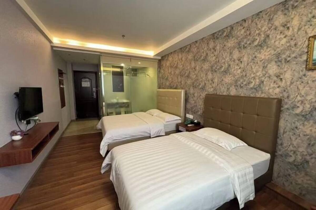 Une chambre d’hôtel avec deux lits, une télévision, une salle de bain et un mur en marbre.