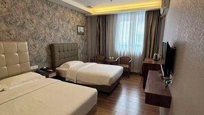 Hotelkamer met twee bedden, een klein tafeltje, een stoel, een televisie en een raam met gordijnen.
