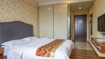 A hotel room with a bed, a bedside table, a TV, and a wardrobe.