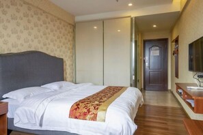 Een hotelkamer met een bed, nachtkastje, televisie en kledingkast.