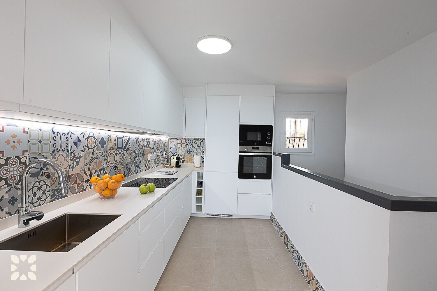 A modern kitchen with white cabinetry, a patterned backsplash, and a built-in oven.