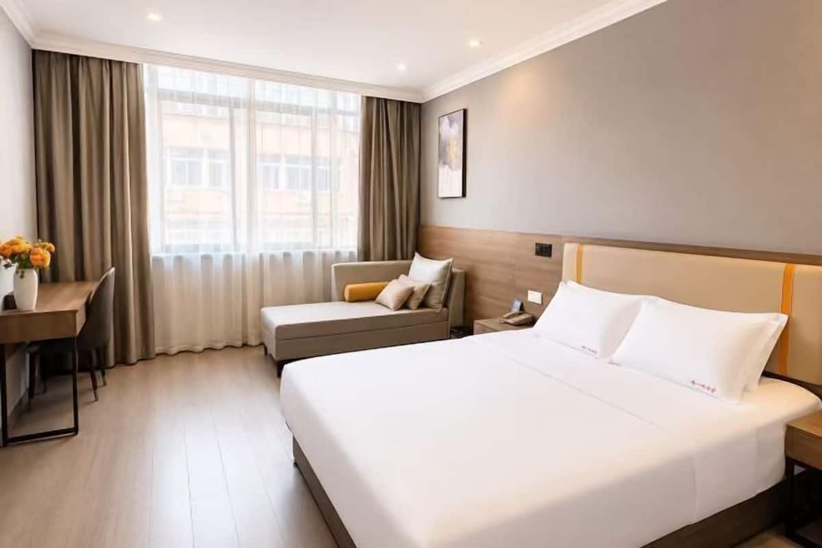 Ein Hotelzimmer mit einem großen Bett, einem Schreibtisch und einem Stuhl.