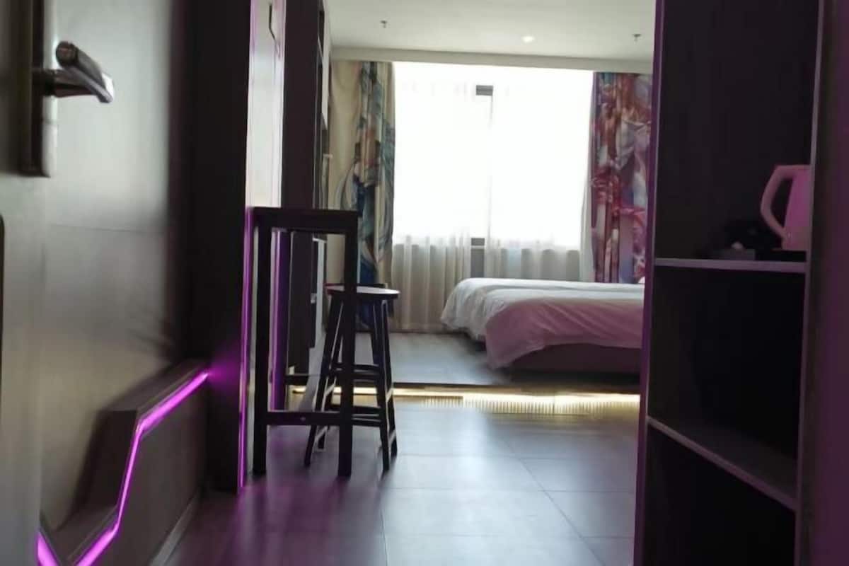 Ein Hotelzimmer mit Bett, Schreibtisch und Stuhl. Ein Fenster mit Vorhängen bietet einen Blick nach draußen.